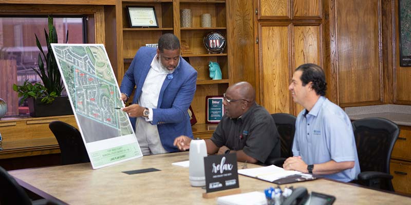 Water and wastewater operators presenting a large aerial plan of an urban neighborhood in a conference room