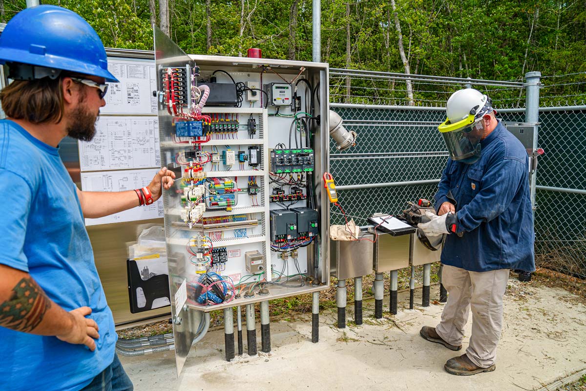 Two wastewater operators servicing an industrial treatment plant electrical controls system